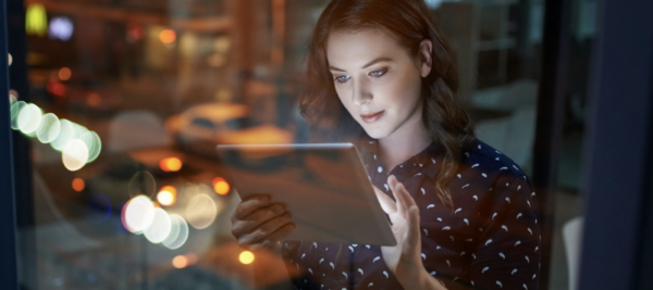 woman holds ipad and looks at it in dark office room