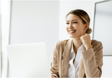 Lady smiling and looking out to the window with laptop in front of her