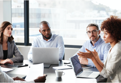 A group of business professionals having a meeting in an office setting with computers and papers on the table