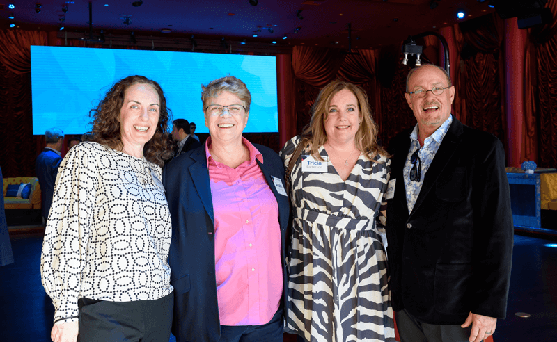 4 smiling WideOrbit employees at a conference