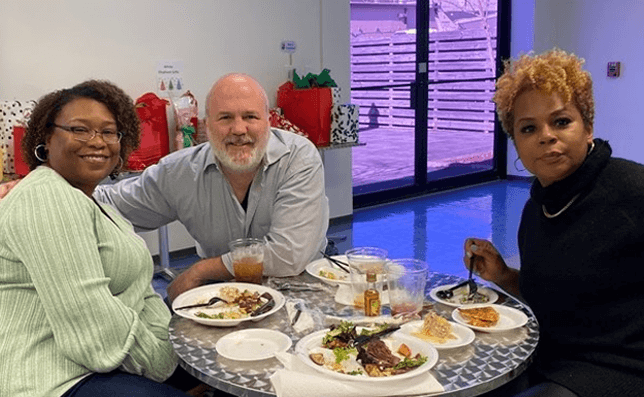 3 WideOrbit employees eating at a company Christmas party