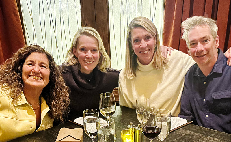 4 smiling WideOrbit employees at a conference dinner