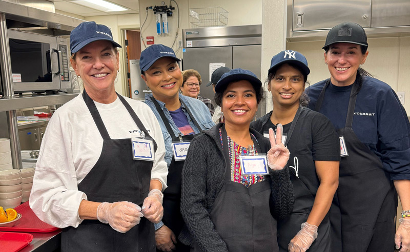 7 smiling WideOrbit employees at a kitchen volunteering